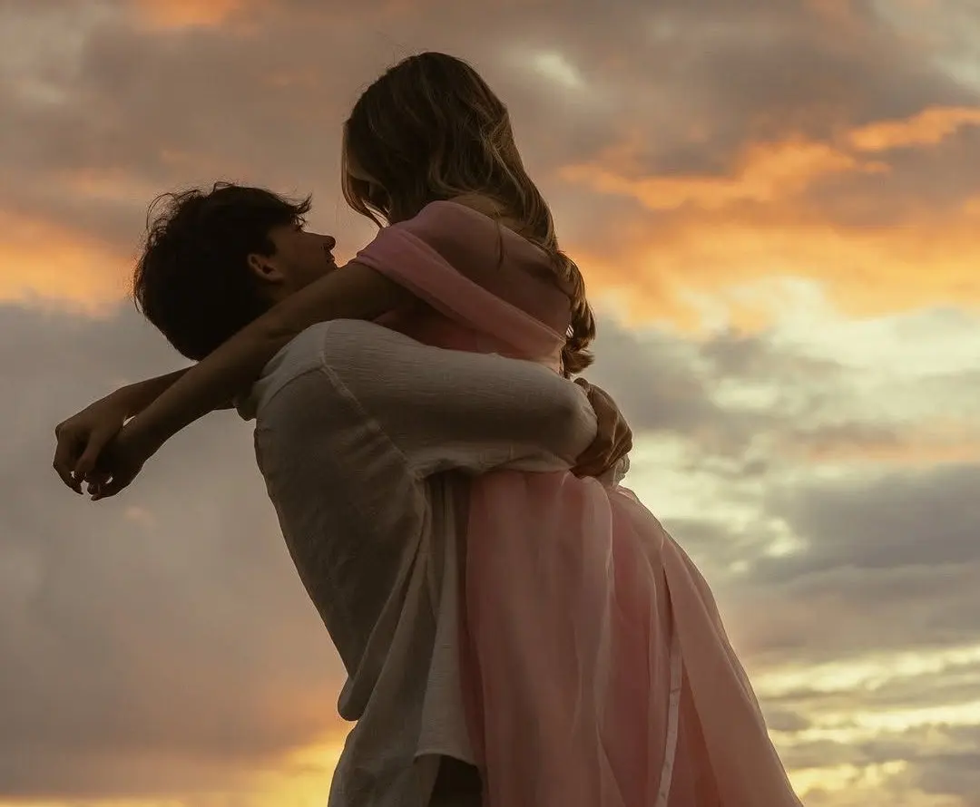A couple holding each other outdoors at sunset, suggesting steady relationship care after disappointment