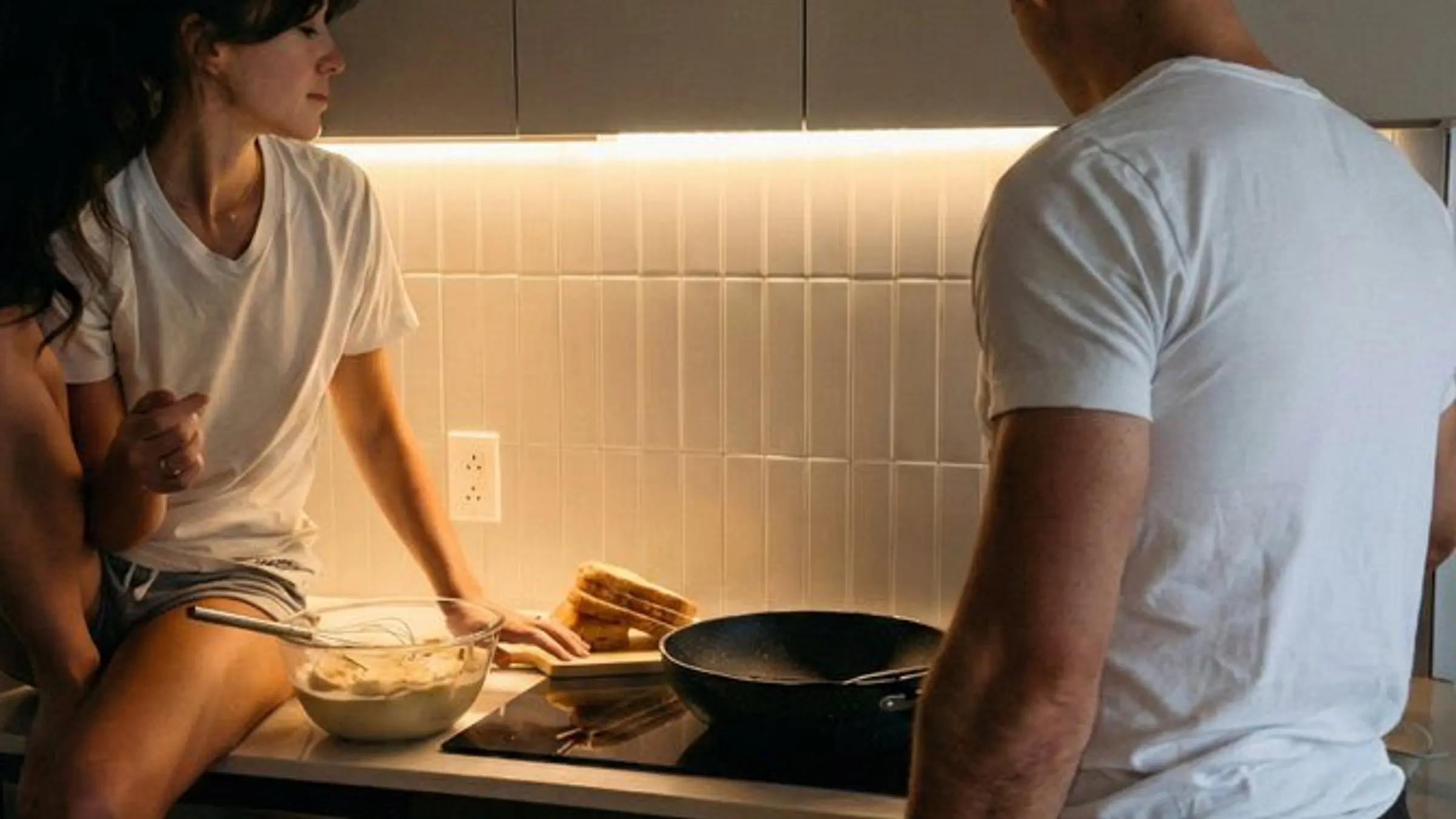 Two adults having a serious kitchen conversation about relationship boundaries