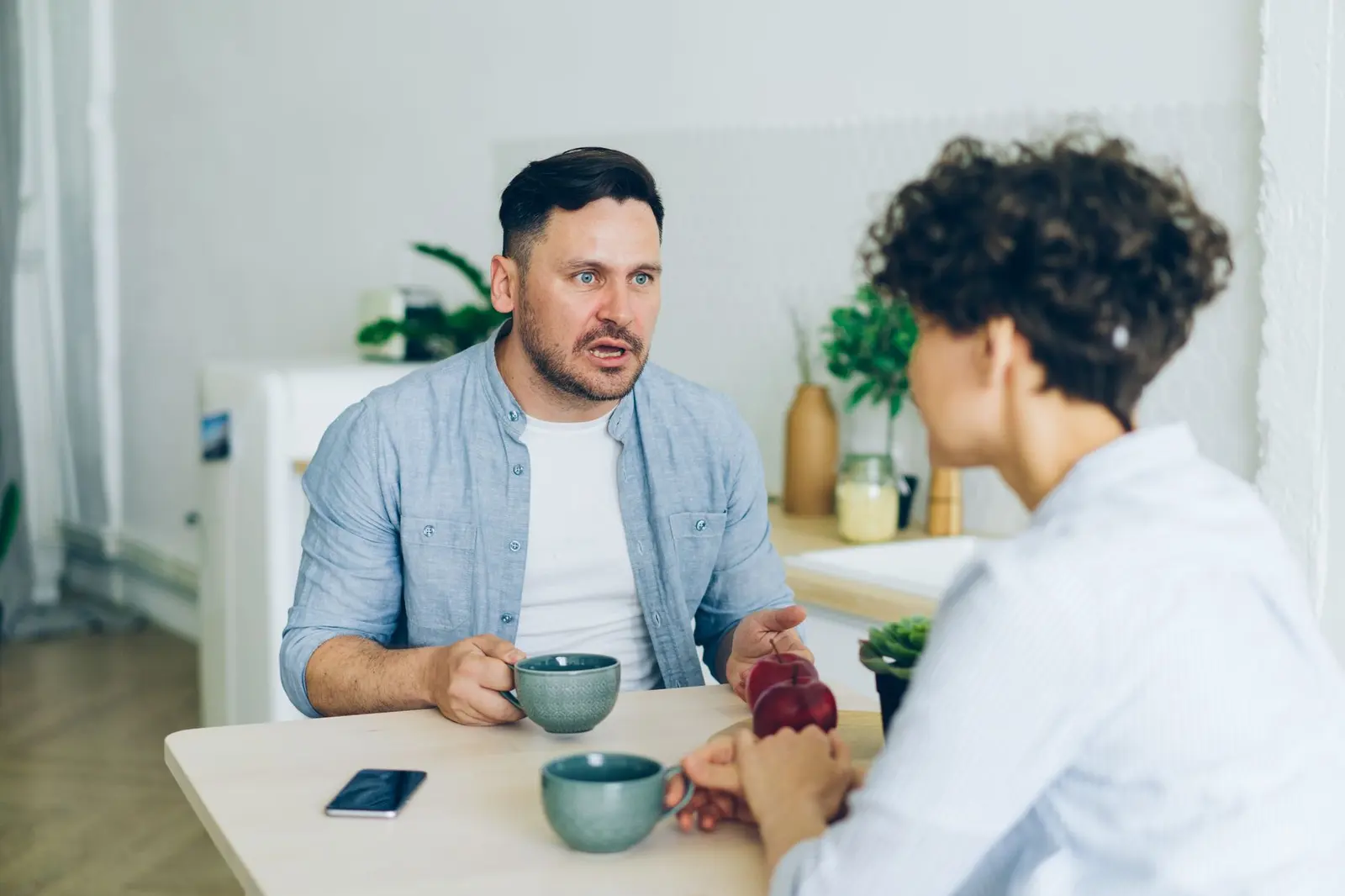 A couple having a serious but calm kitchen table conversation about healthy relationship boundaries
