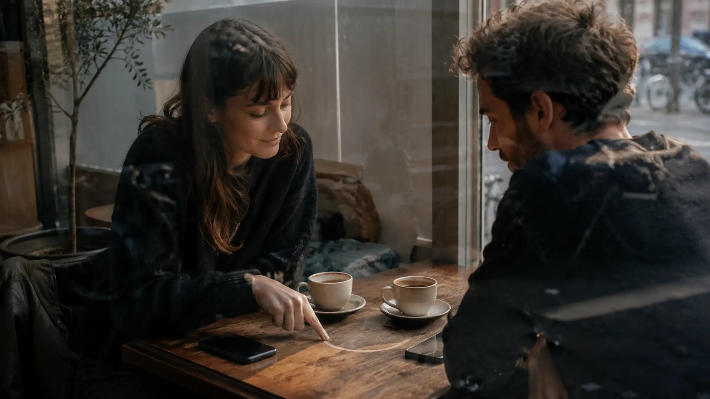 Two people at a cafe table with phones face down and two coffee cups inside a drawn boundary