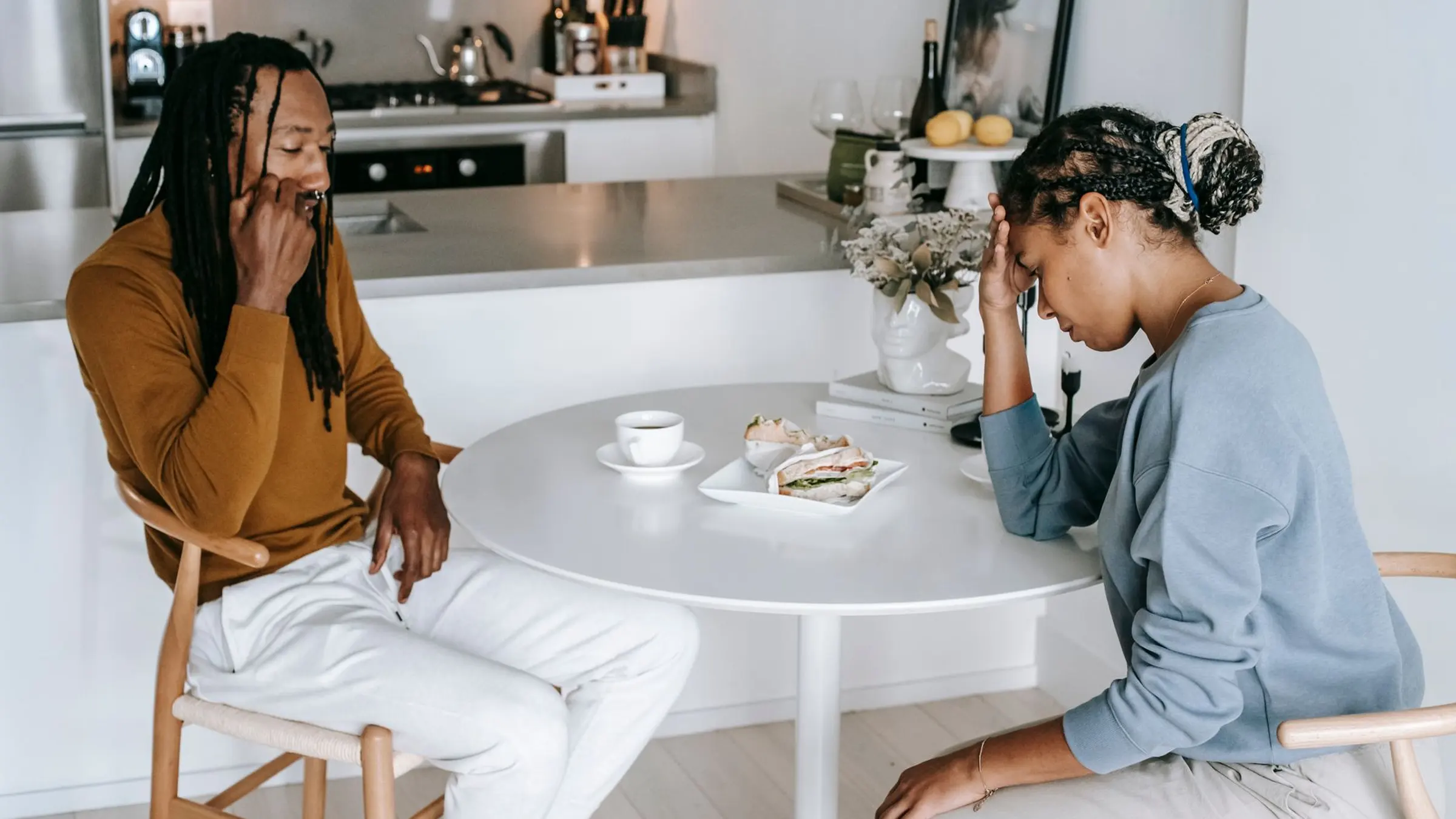 A calm couple sitting apart with warm natural light, leaving comfortable space for a relationship boundary conversation
