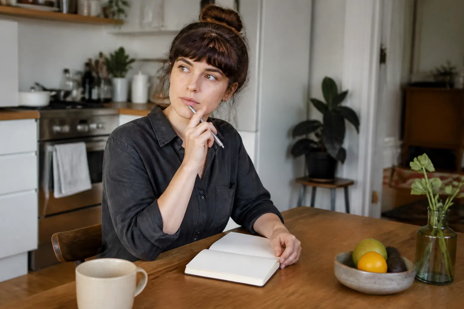 A person at a kitchen table using a notebook to reflect on repeated dating patterns