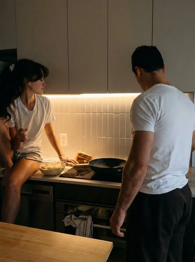 Two adults having a quiet kitchen conversation about relationship boundaries
