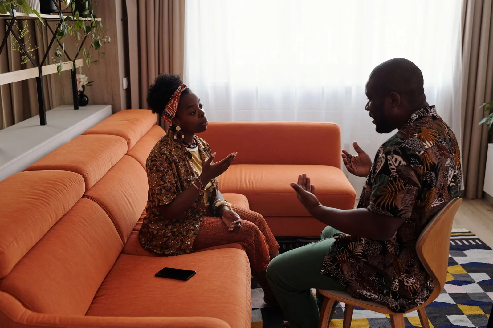 A couple sitting apart on a sofa during an emotional discussion