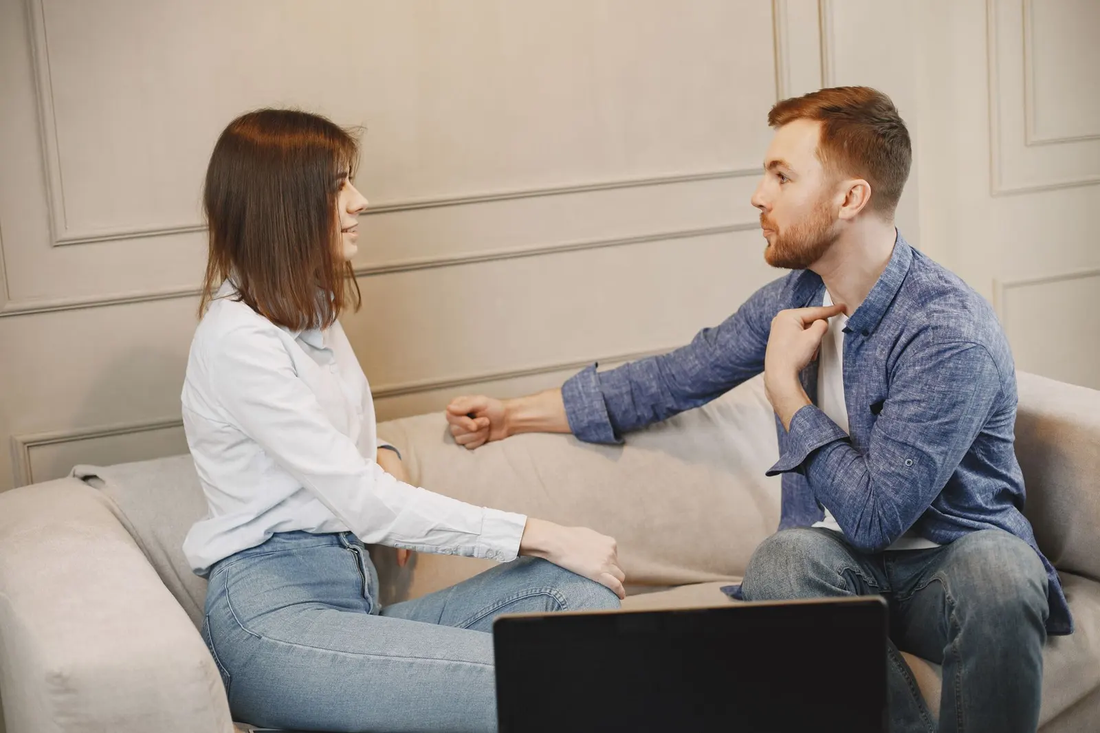 A couple facing each other on a couch while discussing something calmly