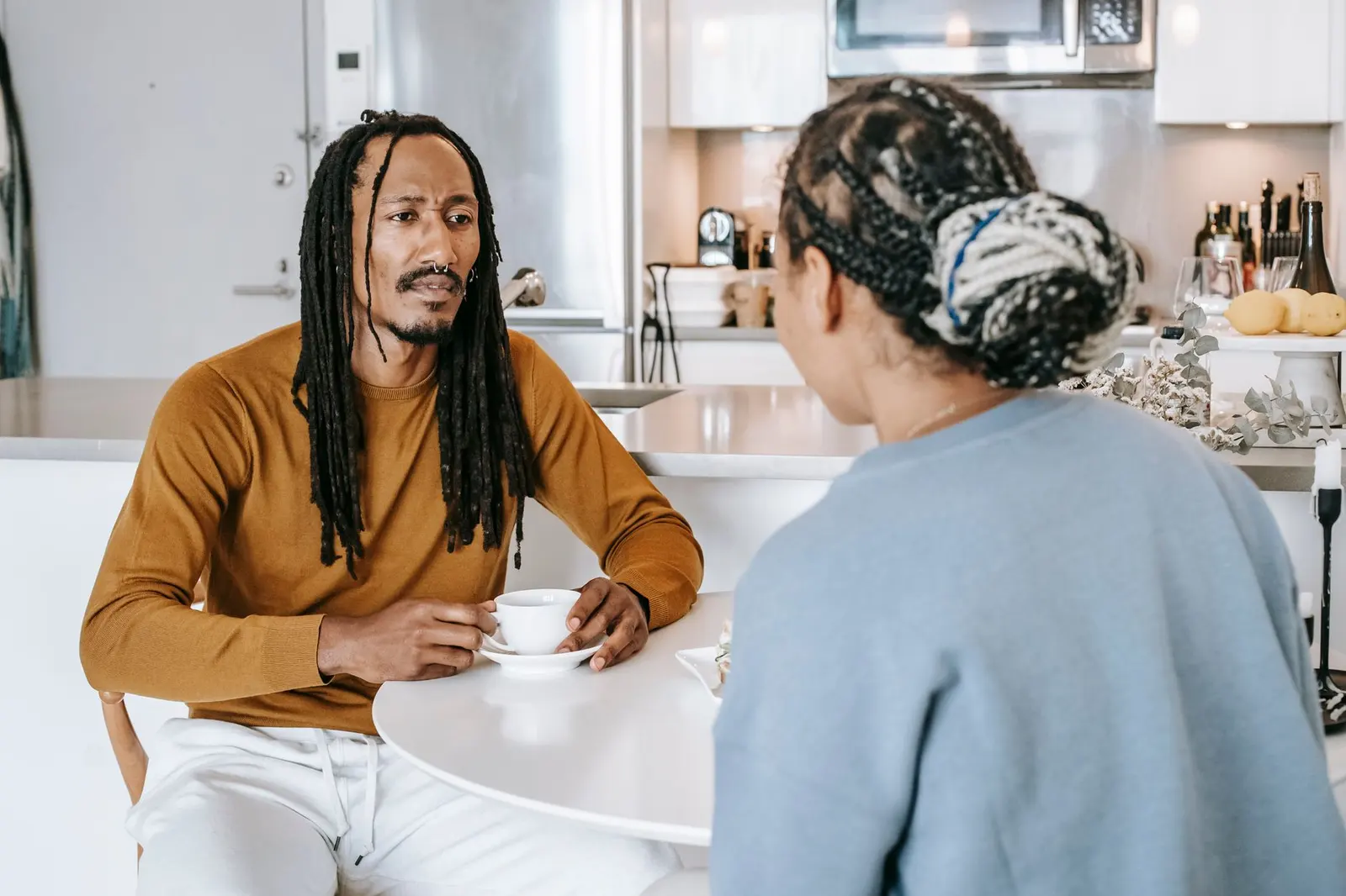 Two people having a serious but grounded kitchen conversation about relationship pace