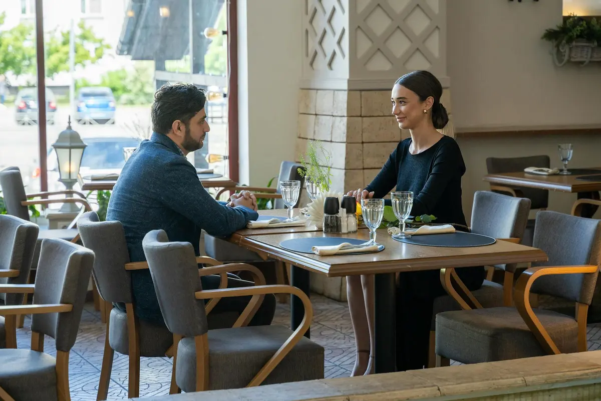 Two people sitting across from each other at a quiet table while having a careful relationship conversation